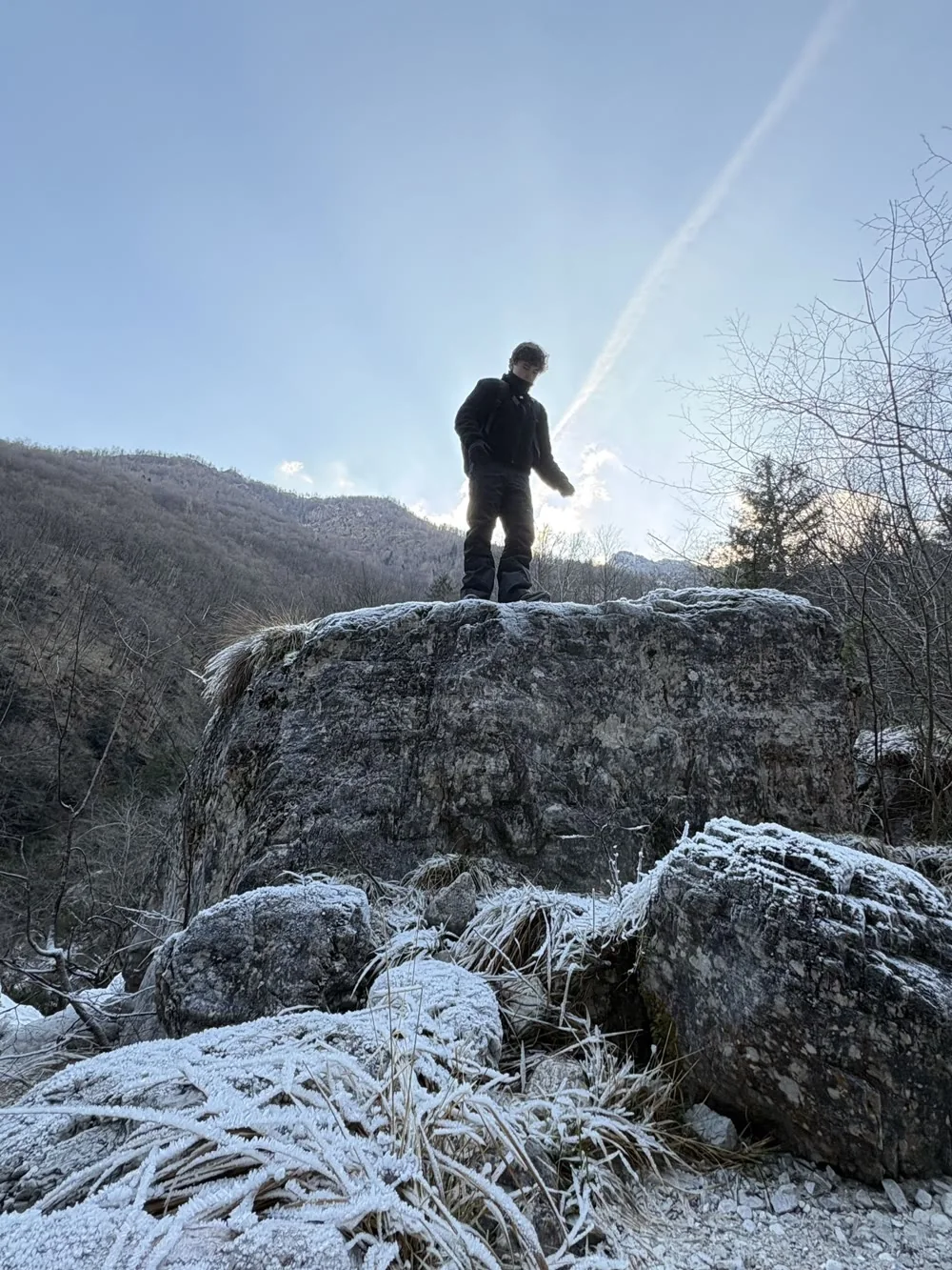 Yente standing on a rock overlooking a mountain valley
